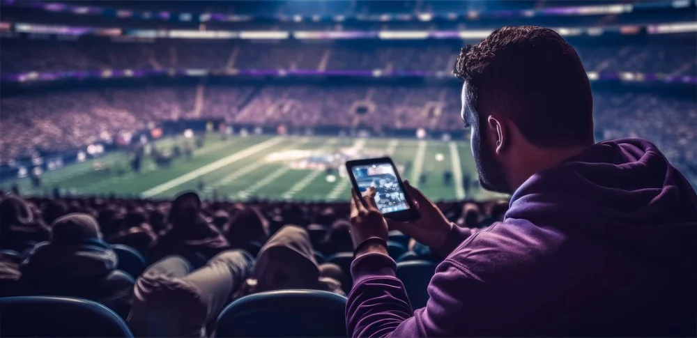 Torcedor apostando pelo celular na arquibancada — Winkey Casino no móvel